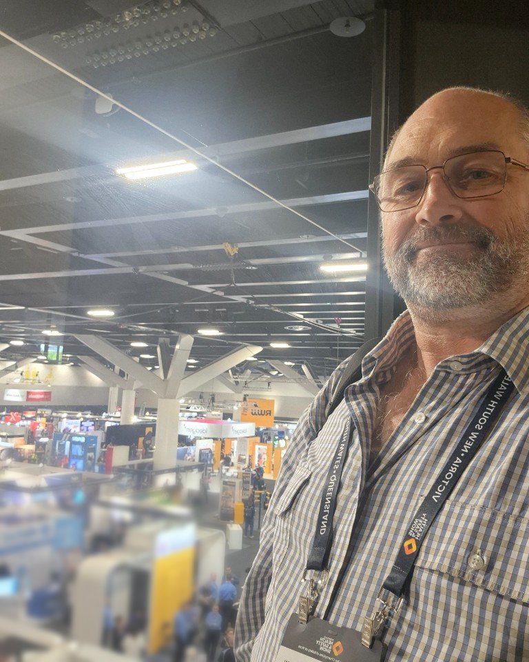 Craig Champion wearing a show lanyard, on a balcony above the exhibition hall at ICC Sydney.